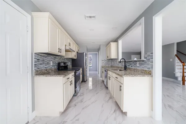 a large kitchen with stainless steel appliances granite countertop a lot of counter space and a sink