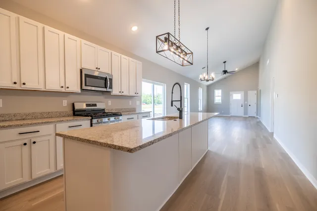 a large kitchen with stainless steel appliances granite countertop a sink a stove and a wooden floors