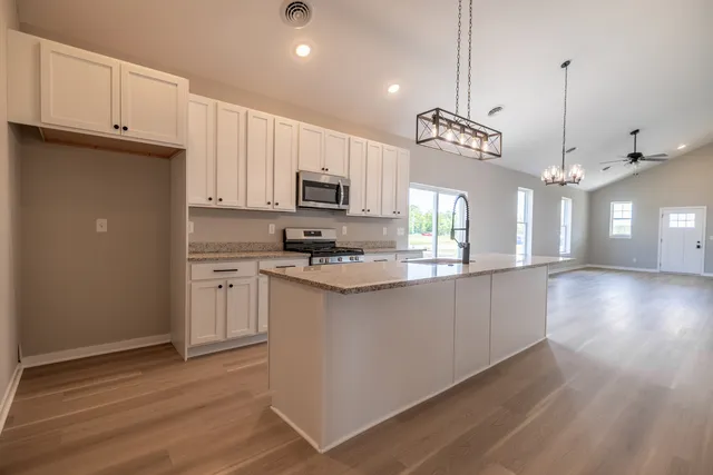 a kitchen with kitchen island granite countertop a sink a counter space appliances and cabinets