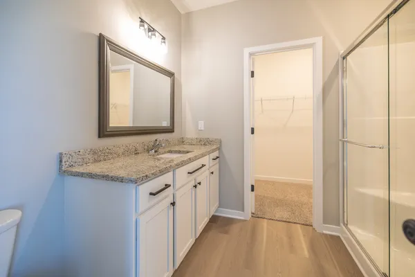 a bathroom with a granite countertop sink a mirror and a shower