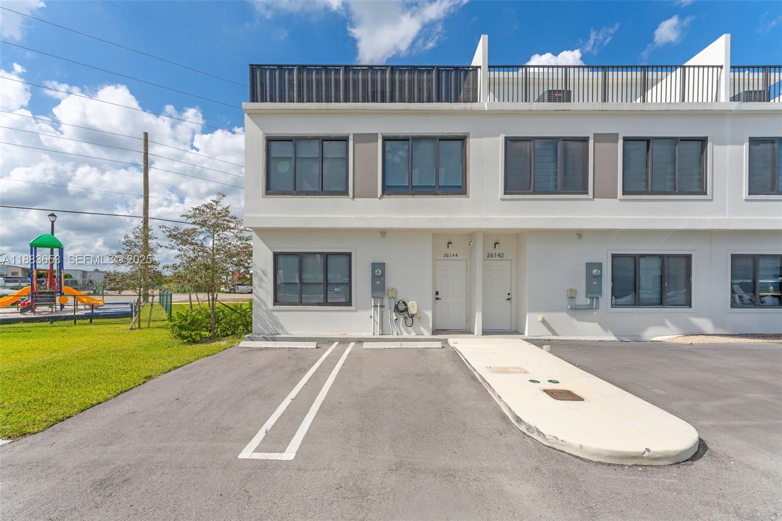 26144 Southwest 146th Court Homestead, FL 33032 - Photo 2 of 35 Back view showing an additional entrance, two assigned parking spaces, and EV charger.
