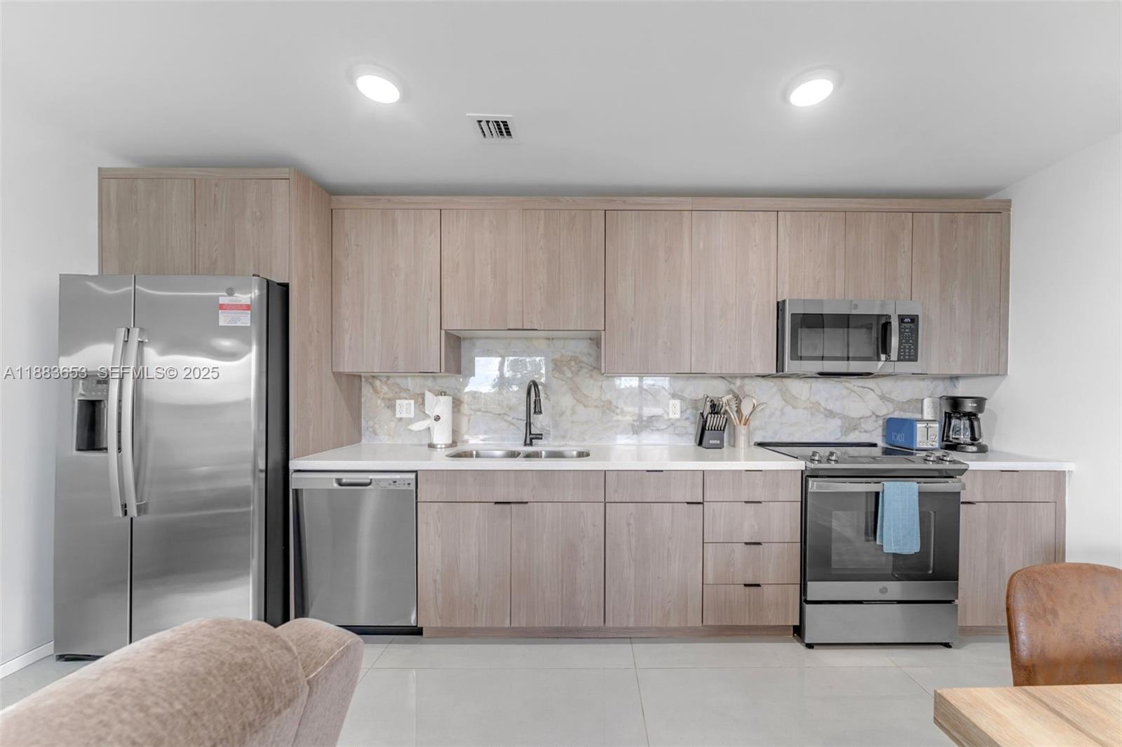 26144 Southwest 146th Court Homestead, FL 33032 - Photo 7 of 35 Modern kitchen with wood cabinets and stainless steel appliances.