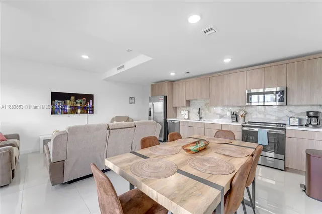 a kitchen with stainless steel appliances granite countertop a stove a sink a dining table and chairs