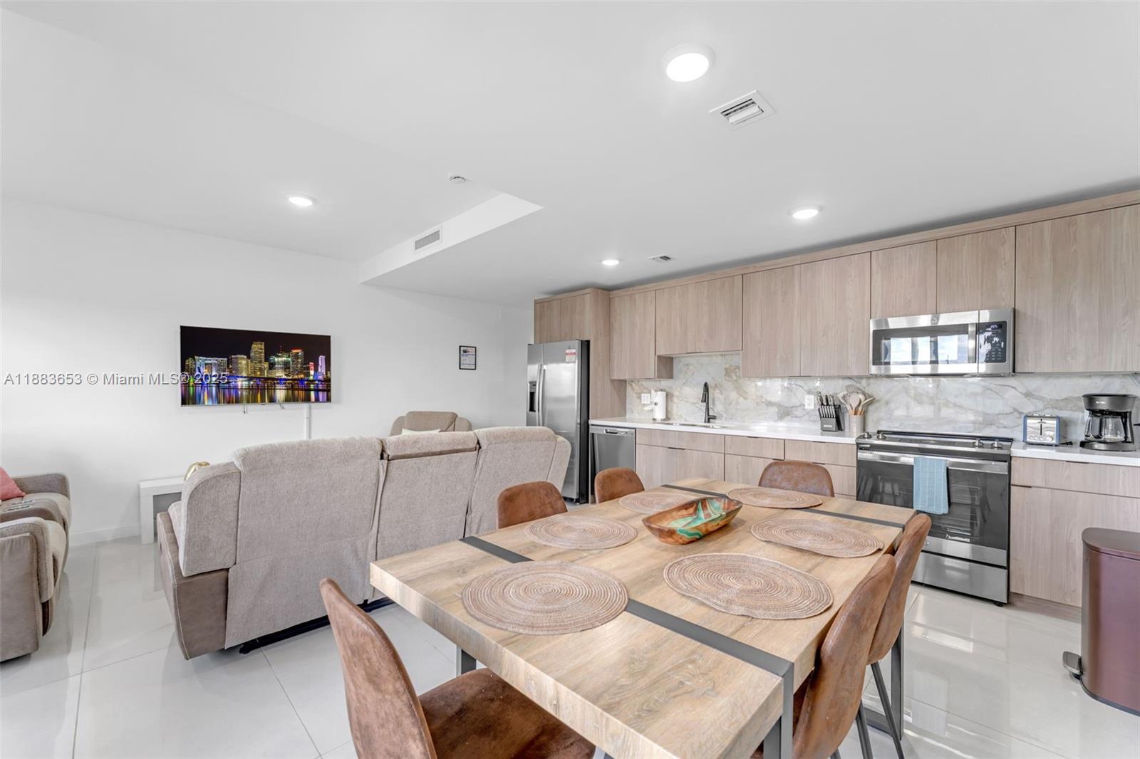 26144 Southwest 146th Court Homestead, FL 33032 - Photo 9 of 35 a kitchen with stainless steel appliances granite countertop a stove a sink a dining table and chairs