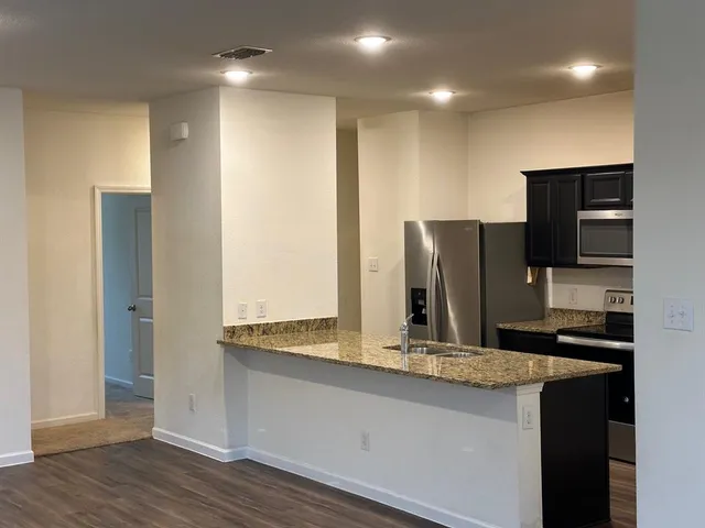 a kitchen with kitchen island granite countertop a refrigerator and a stove top oven