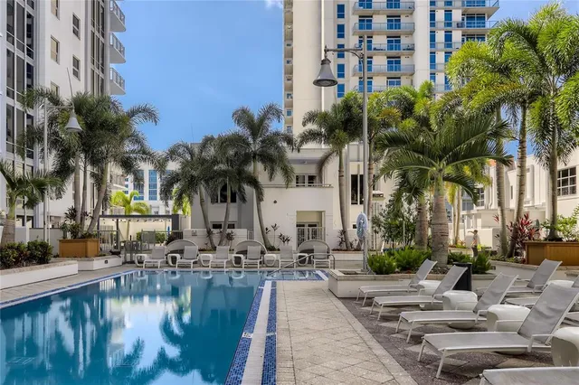 a view of a swimming pool with a lawn chairs and palm trees