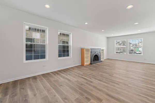 a view of empty room with wooden floor and fireplace