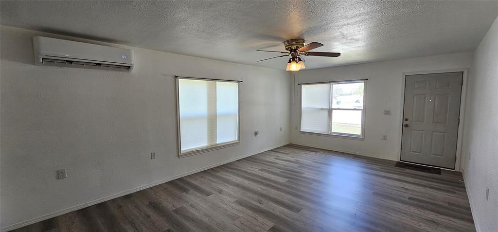 501 South Main Street Eden, TX 76837 - Photo 3 of 20 an empty room with wooden floor chandelier fan and windows