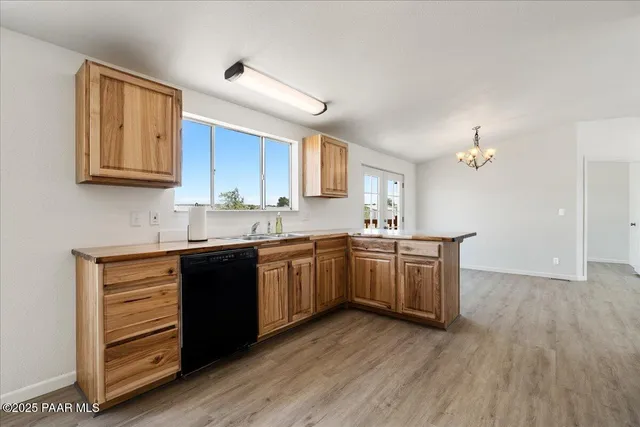 a kitchen with stainless steel appliances granite countertop a stove top oven a sink and a microwave oven on the wooden floor