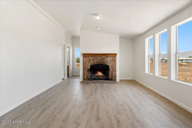 an empty room with wooden floor fireplace and windows