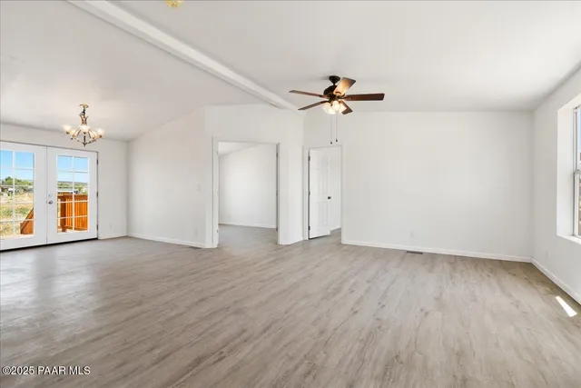 a view of an empty room with window and wooden floor