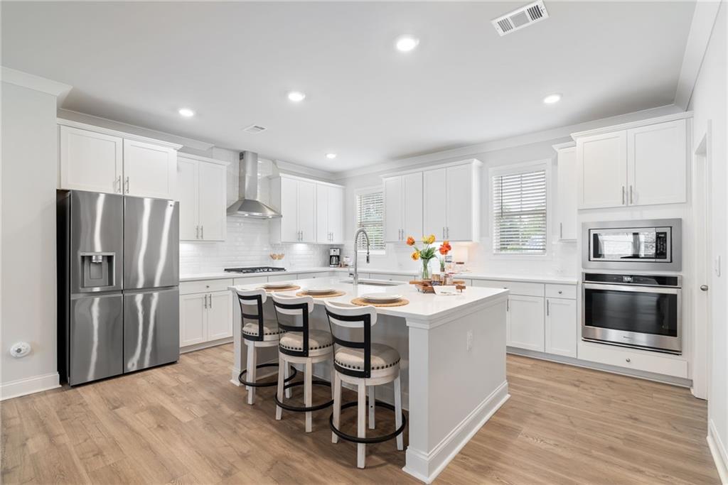 3334 Swallowtail Terrace Duluth, GA 30096 - Photo 5 of 30 a kitchen with kitchen island a white counter space cabinets and stainless steel appliances