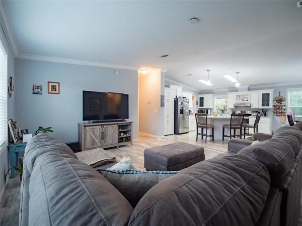 a living room with furniture and kitchen view with wooden floor