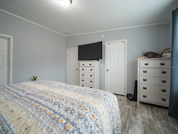 a bedroom with a large bed and a flat tv screen on dresser