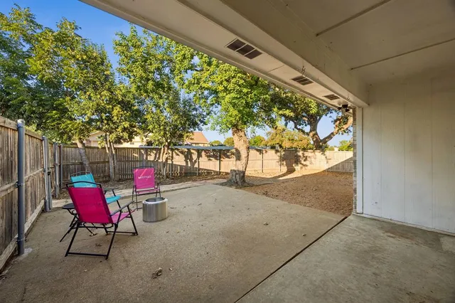 a view of a house with large tree and wooden fence