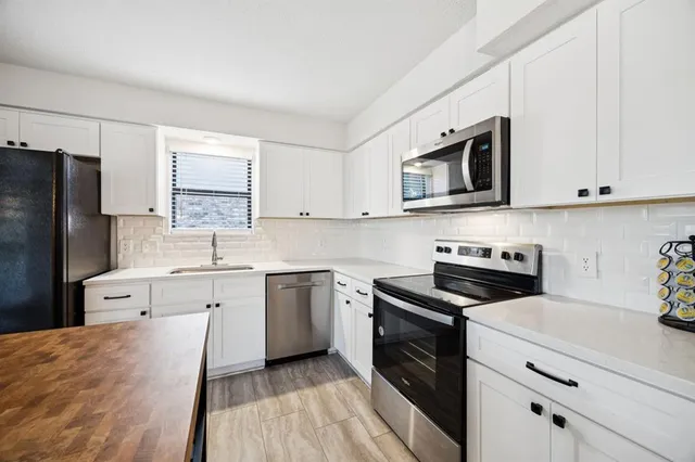 a kitchen with granite countertop cabinets stainless steel appliances and a wooden floor