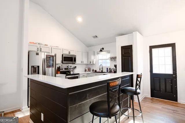 a kitchen with a stove a refrigerator and a dining table with wooden floor