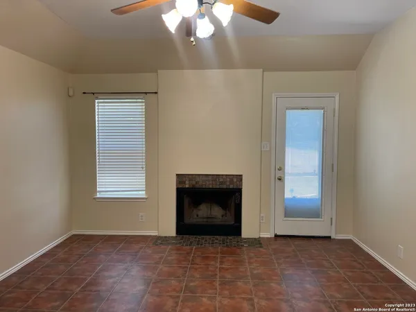 an empty room with windows and fireplace