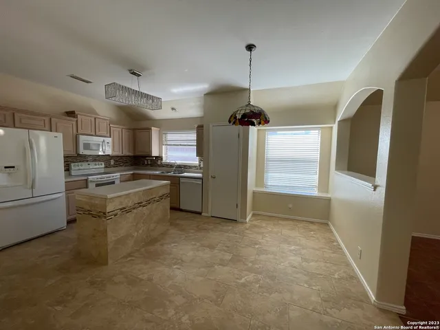 a kitchen with stainless steel appliances kitchen island granite countertop a refrigerator a stove a microwave oven a sink with island in the background