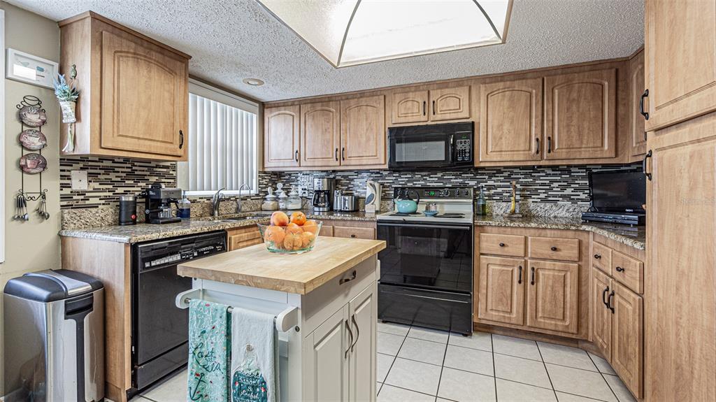 7 Elgin Place, Unit 301 Dunedin, FL 34698 - Photo 10 of 35 a kitchen with granite countertop a sink stove top oven and cabinets