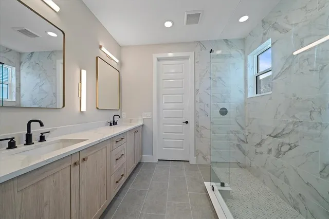 a bathroom with a double sink shower and a mirror