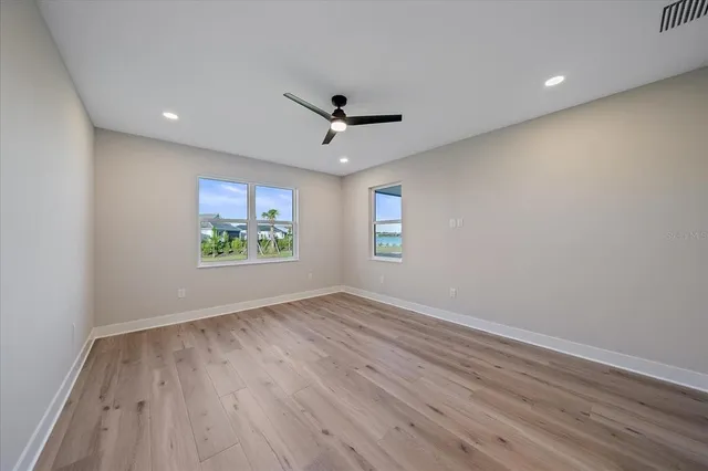 an empty room with windows and ceiling fan