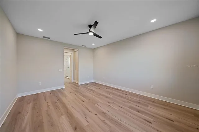 a view of empty room with wooden floor and fan