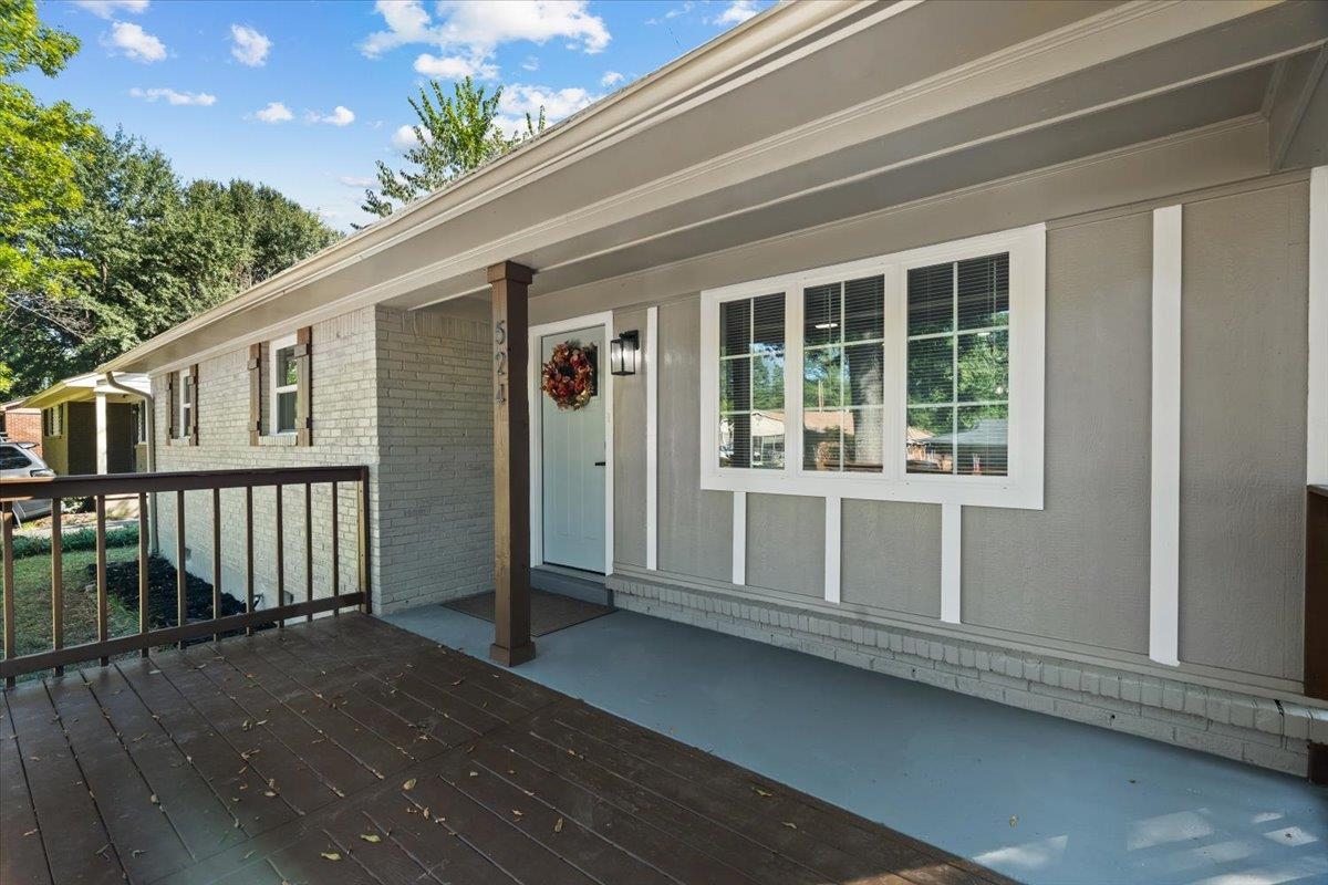 524 McDermitt Road Memphis, TN 38120 - Photo 2 of 32 Expansive front deck, painted brick exterior, white paneled front door, large bay window with white trim, and a contemporary exterior sconce