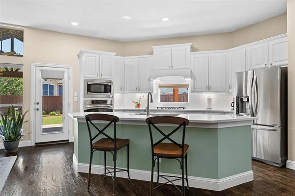 a kitchen with stainless steel appliances a table chairs refrigerator and microwave