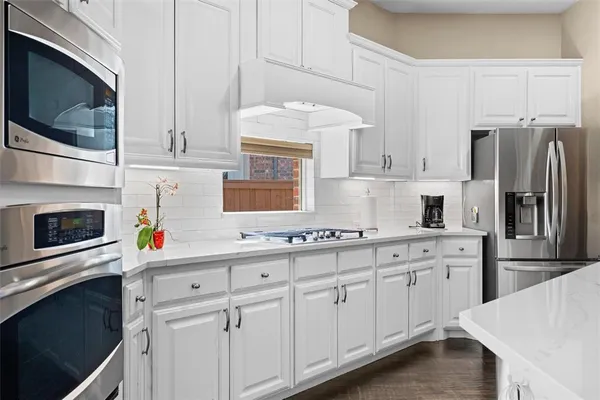 a kitchen with stainless steel appliances white cabinets and a stove top oven