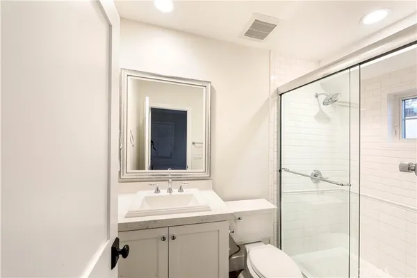 a bathroom with a granite countertop sink toilet mirror and shower
