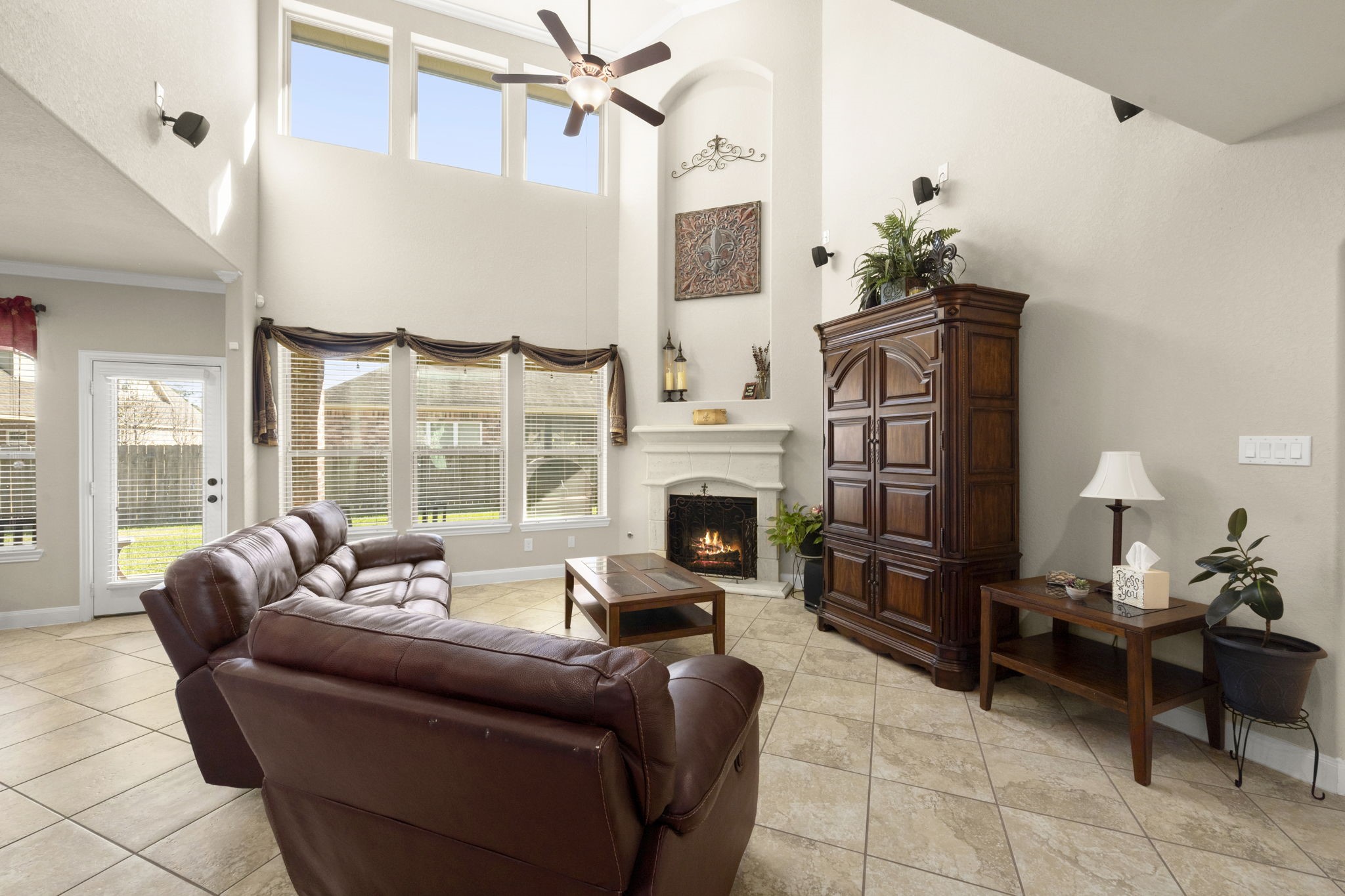 25306 Doyle Sands Court Spring, TX 77389 - Photo 11 of 35 Light-filled living room with soaring ceilings, large windows, and a warm fireplace centerpiece. Surround sound system conveys with the home.