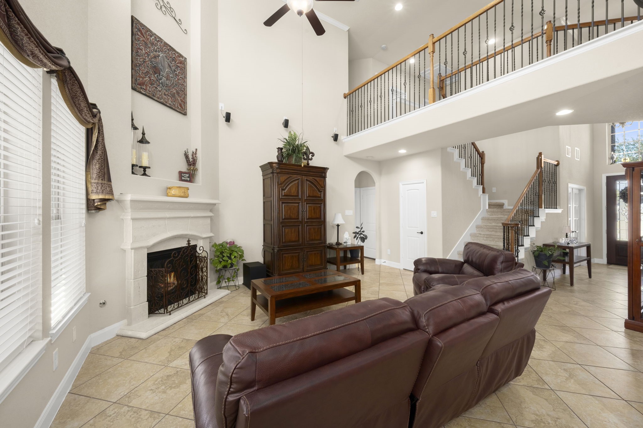 25306 Doyle Sands Court Spring, TX 77389 - Photo 12 of 35 Open living space featuring high ceilings, a cozy fireplace, and an elegant iron spindle staircase overlooking the room. Surround sound system conveys with the home.