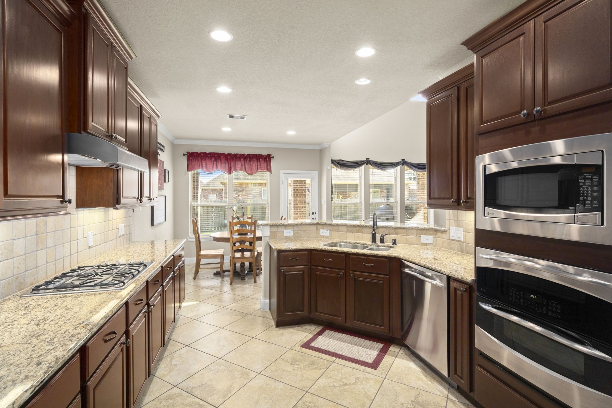 25306 Doyle Sands Court Spring, TX 77389 - Photo 15 of 35 Inviting kitchen with granite countertops, dark cabinetry, stainless steel appliances, and a sunny breakfast nook.