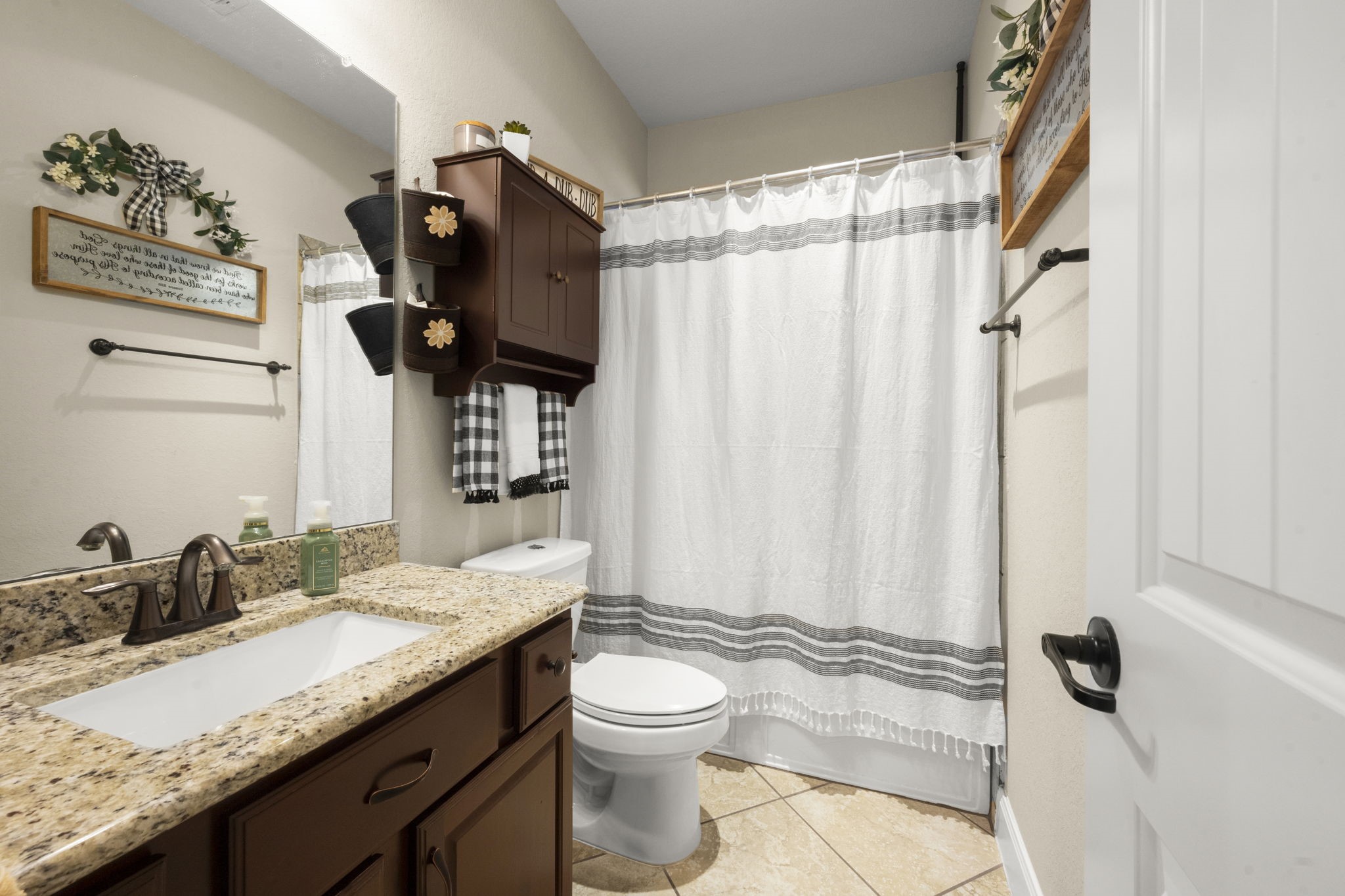 25306 Doyle Sands Court Spring, TX 77389 - Photo 24 of 35 Inviting first-floor bathroom with granite countertops, warm wood cabinetry, and a shower-tub combination. Just down the hall from the first floor bedroom.