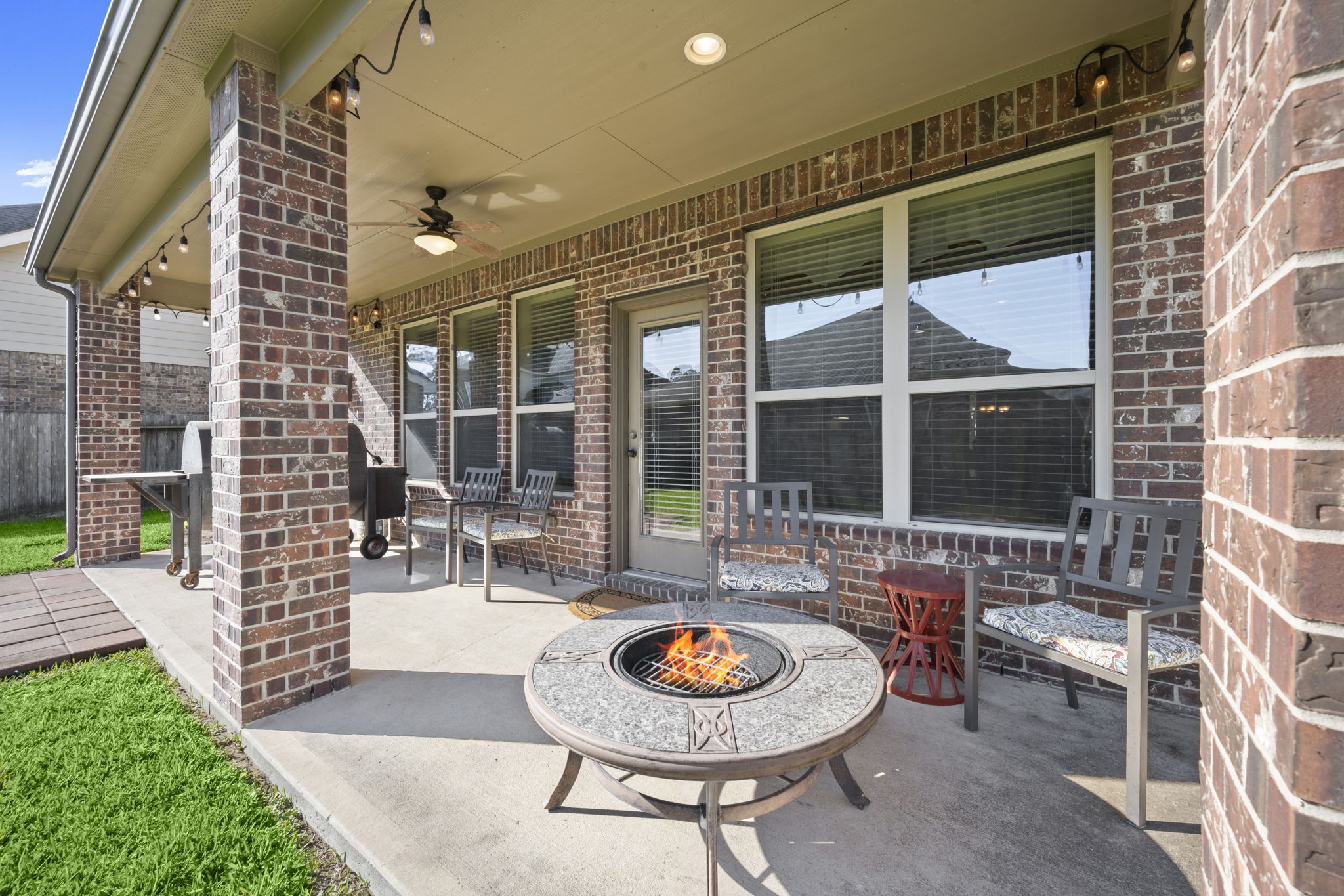 25306 Doyle Sands Court Spring, TX 77389 - Photo 6 of 35 Cozy covered patio with brick detail, seating space, and ambient lighting—perfect for evenings outdoors. Outdoor string lights will convey.