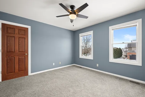 an empty room with windows and ceiling fan