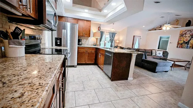 a large kitchen with stainless steel appliances kitchen island granite countertop a large counter top a stove a sink a refrigerator and a cabinets