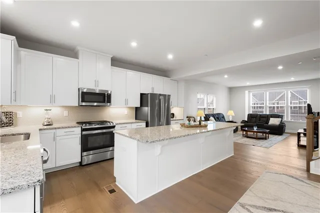 a kitchen with stainless steel appliances granite countertop a stove top oven a sink a stove a dining table and chairs