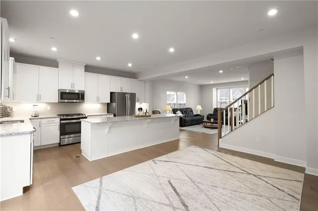 a large white kitchen with lots of counter top space a sink stainless steel appliances and cabinets