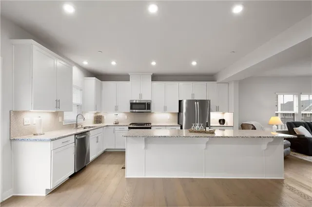 a kitchen with stainless steel appliances granite countertop a stove top oven a sink and white cabinets