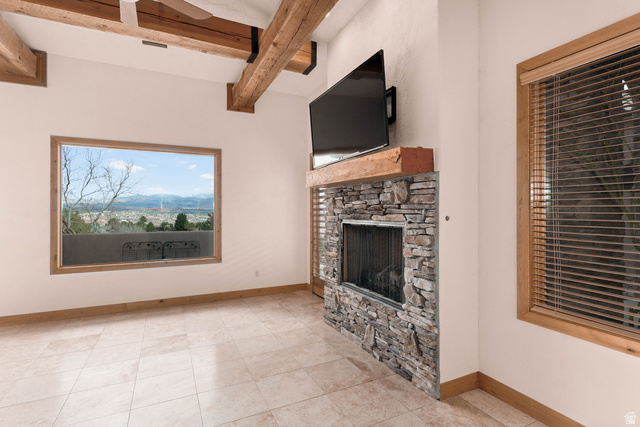 2464 East Granite Way St. George, UT 84790 - Photo 73 of 106 Unfurnished living room featuring a fireplace, beamed ceiling, and light tile patterned flooring
