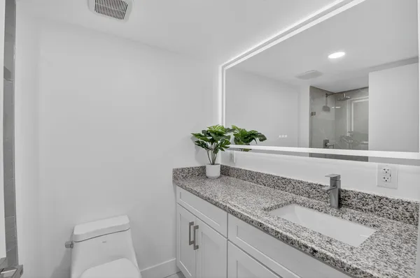 a bathroom with a granite countertop sink and a mirror