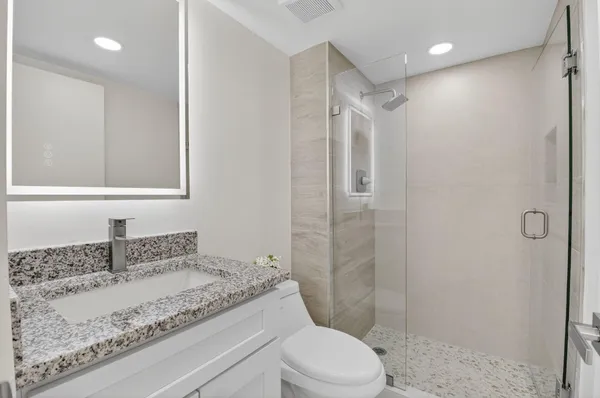 a bathroom with a granite countertop sink toilet and shower