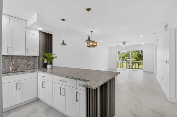a kitchen with white cabinets and chandelier