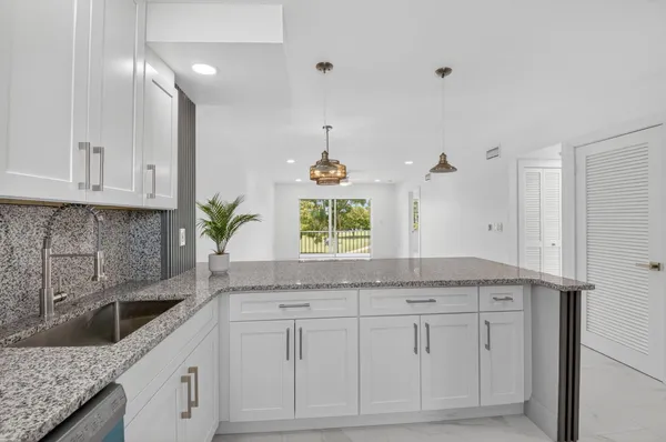 a kitchen with granite countertop white cabinets and a sink
