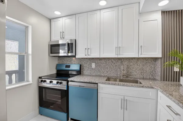 a kitchen with stainless steel appliances granite countertop a stove a sink and a microwave