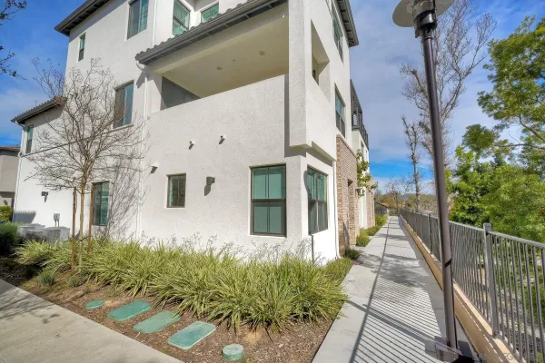 a view of a white house with a large windows and flower plants