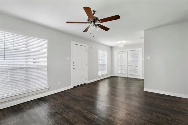 a view of an empty room with wooden floor and a window