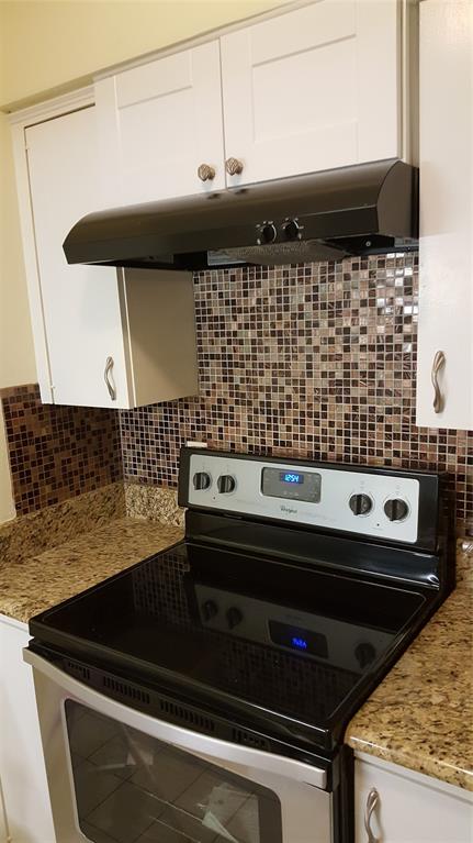 4859 Cedar Springs Road, Unit 358 Dallas, TX 75219 - Photo 5 of 12 Kitchen with stove, white cabinets, range hood, and backsplash